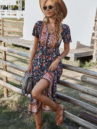 Woman wearing a stylish bohemian midi dress with floral patterns, posing outdoors in a sunny environment.