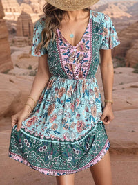 boho summer mini dress worn by a woman in a bohemian floral pattern, standing outdoors against a rocky landscape