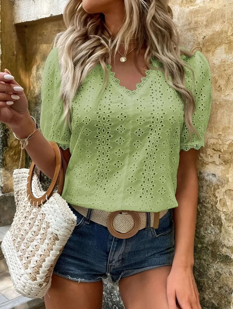 Women wearing a lace embroidery blouse in green, featuring short sleeves and a V-neck design, styled with denim shorts.