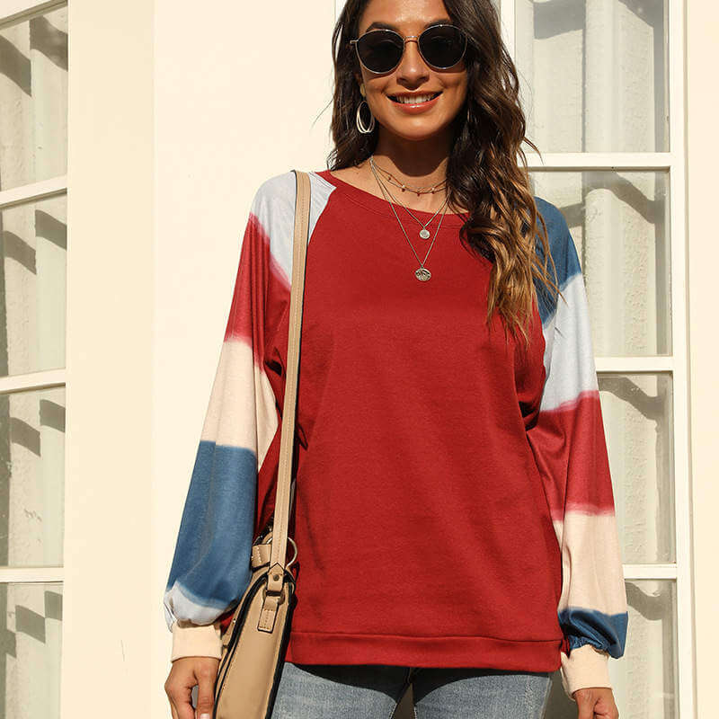 A woman wearing a baggy tunic sweatshirt with long striped sleeves and sunglasses, showcasing a casual look.